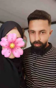 Photo of a man and a woman. The man is wearing a striped polo shirt and has dark hair, brown eyes, and a mustache & goatee. The woman is wearing a black hijab and has a pink flower obscuring her face.