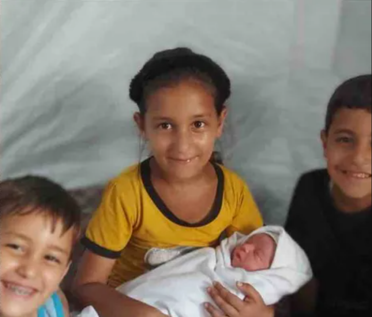 Photo of four siblings. Two boys on the outside, and one girl in the center holding a very young baby.